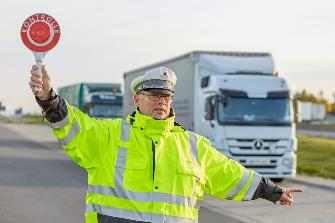 
Ein Mitarbeiter des BALM hält Fahrzeuge mit einer roten Kelle an, um eine Kontrolle durchzuführen