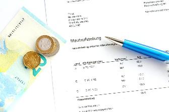 
Auf einer ausgedruckten Mautaufstellung liegen ein Kugelschreiber und etwas Bargeld.