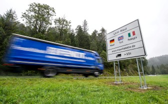 
Ein Lkw-Fahrer fährt an einem Maut-Schild vorbei.